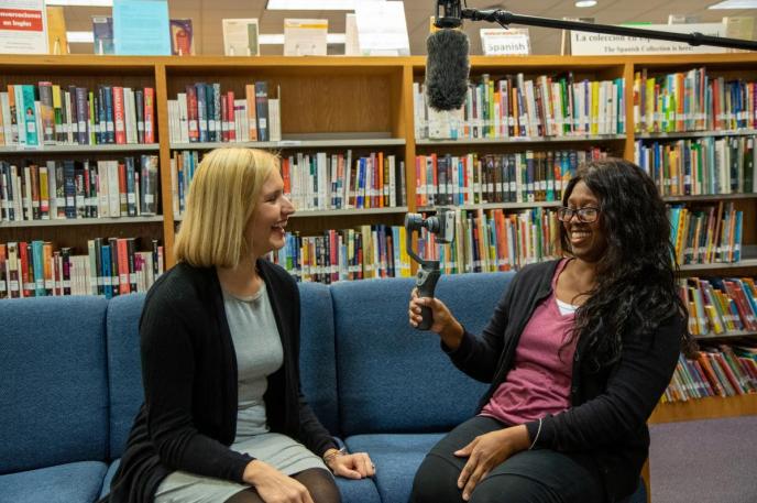 A cellphone video kit with boom mic in use. Two women use a cellphone video kit from Charlotte Mecklenburg Library with a boom mic overhead .