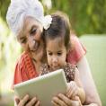 Older adult reading with child on a mobile tablet.